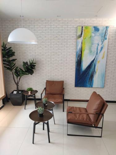 a lobby with two chairs and tables and a painting at Hotel 99 Seri Kembangan Serdang in Seri Kembangan