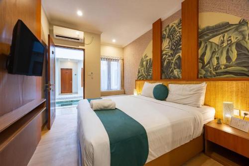 a bedroom with a large bed and a flat screen tv at Cove Vin Stay Petanu in Pesanggaran
