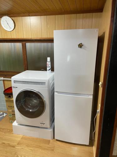 a refrigerator and a microwave next to a washing machine at ゲストハウス こごみ庵 in Shikokuchuo