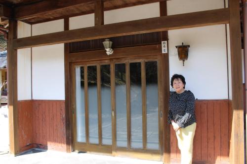 a woman standing in the doorway of a building at ゲストハウス こごみ庵 in Shikokuchuo