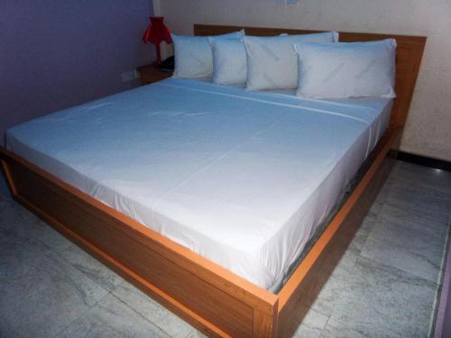 a large bed with a wooden frame and white sheets at Best Connection Airport Hotel in Lagos