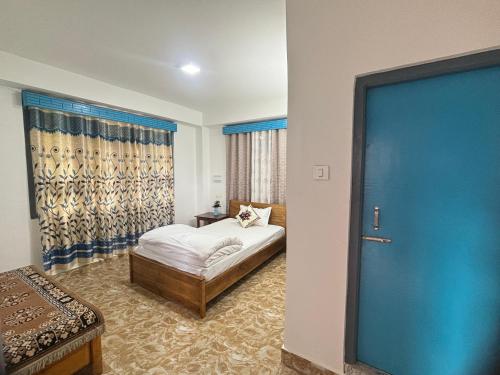 a bedroom with a bed and a blue door at Mountain Whisper Homestay Yuksom in Pemayangtse