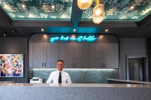 a man in a tie standing behind a counter at Brit Hotels Earls Court in London