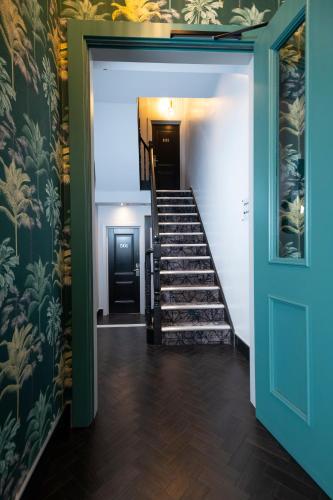 a hallway with a staircase with a blue door at Brit Hotels Earls Court in London