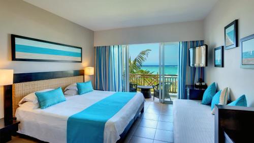 um quarto de hotel com uma cama e vista para o oceano em Pearle Beach Resort & Spa em Flic-en-Flac