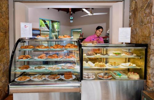 a woman standing behind a display case in a bakery at Mandara Rosen Yala, Kataragama in Kataragama