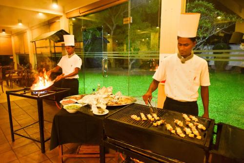 two men in chefs hats cooking food on a grill at Mandara Rosen Yala, Kataragama in Kataragama