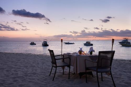a table on the beach with boats in the water at Pearle Beach Resort & Spa in Flic-en-Flac