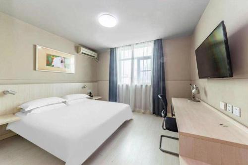 a bedroom with a large white bed and a flat screen tv at Jinjiang Inn Nanjing Xinjiekou Traditional Chinese Medicine Hospital Chaotiangong West Street in Nanjing