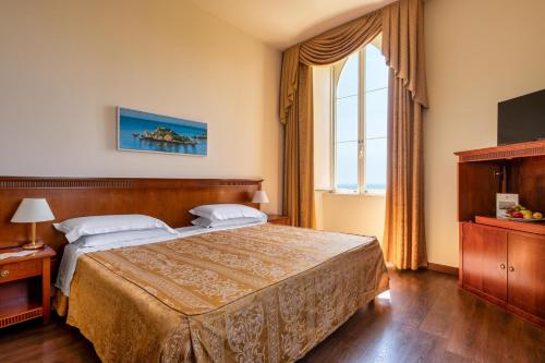 a bedroom with a large bed and a window at Excelsior Palace Hotel in Taormina