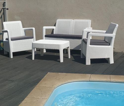 three wicker chairs and a table next to a pool at Luna Bianca in Had Nes