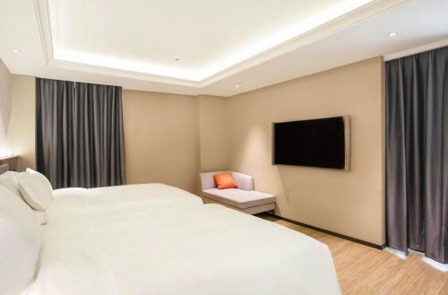 a hotel room with two beds and a flat screen tv at Baoli International Hotel - Yangjiang Baili Plaza in Yangjiang