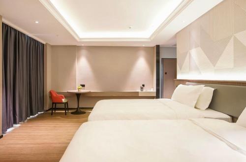a hotel room with two beds and a desk at Baoli International Hotel - Yangjiang Baili Plaza in Yangjiang