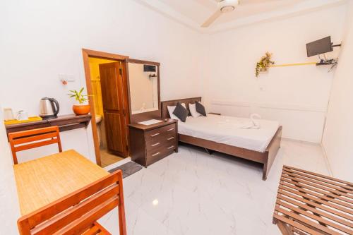 a bedroom with a bed and a desk and a mirror at Cinnamon Airport Residencies in Katunayaka