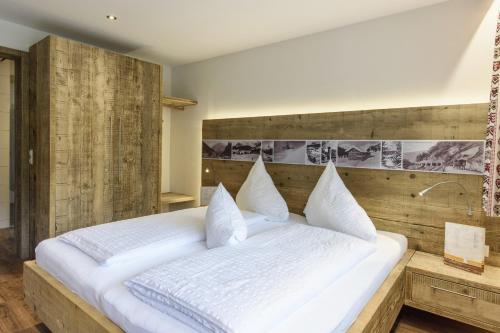 a bedroom with a large white bed with a wooden headboard at Gasthof-Pension Wulfenia in Gargellen