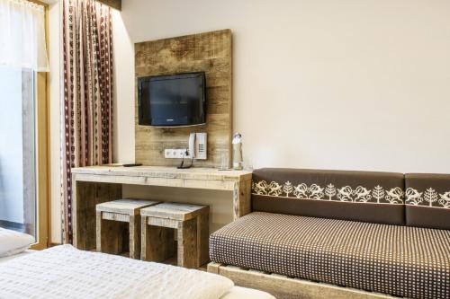 a hotel room with a bed and a tv on a wall at Gasthof-Pension Wulfenia in Gargellen