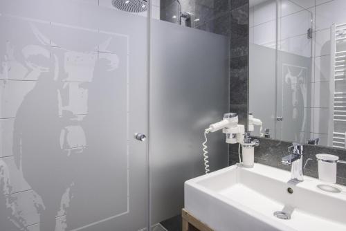 a white bathroom with a sink and a shower at Gasthof-Pension Wulfenia in Gargellen