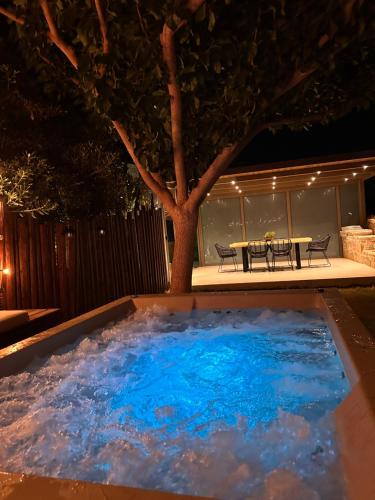 a large pool of water in a backyard at night at Villa Repsimia with Private Jacuzzi in Kókkinos Pírgos