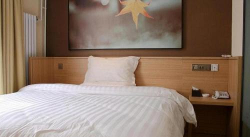 a bedroom with a white bed with a picture on the wall at 7 Days Inn Zhangjiakou Chongli Yuxing Road in Zhangjiakou