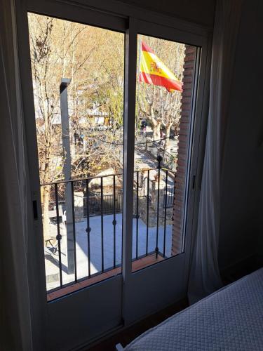 a window with a view of a balcony with a flag at Casa de Manuel in Pinos Genil
