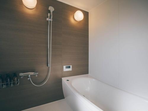 a bathroom with a bath tub and a shower at ワイナリーや酒蔵巡りなどにおすすめの宿 小諸市 築100年の古民家 Chojuro -長寿楼- in Komoro