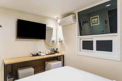 a bedroom with a bed and a tv on the wall at 넘버25호텔 길동점 in Seoul