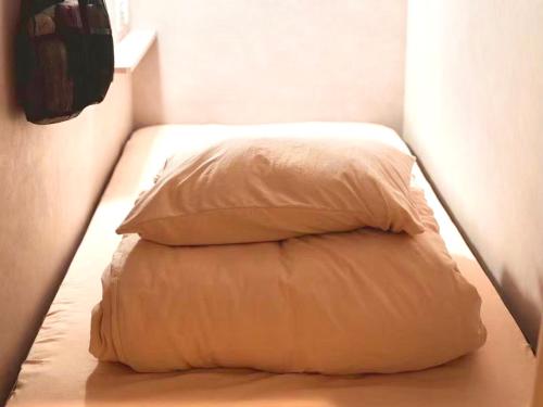 a stack of pillows on a bed in a room at HOTEL minimumms女性専用カプセルホテルWomen only hotel in Naha