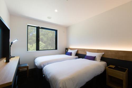 two beds in a room with a window at Always Niseko in Niseko