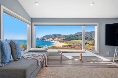 a living room with a large window with a view of the beach at Distinguished Oceanfront Point Estate with Iconic Beach Mountain Vistas in Montara