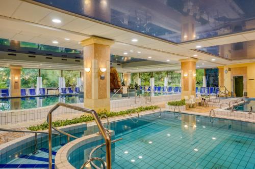 a large swimming pool in a hotel with blue tiles at Ensana Grand Margaret Island in Budapest