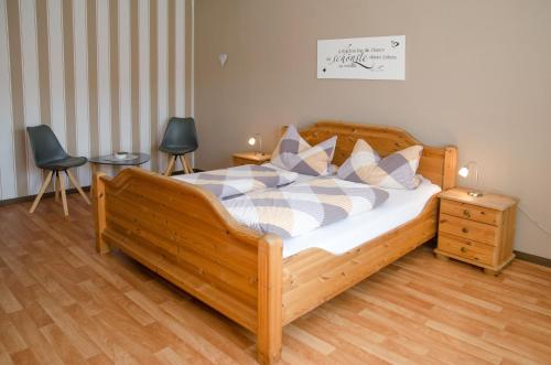 a bedroom with a wooden bed and two chairs at Ferienhaus Voß, 65260 in Moormerland