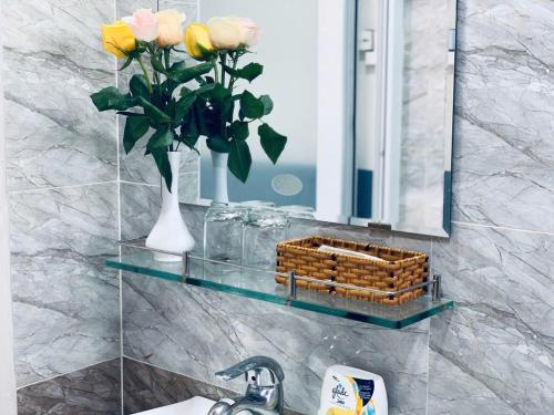 un lavandino del bagno con un vaso di rose e uno specchio di August Inn Da Lat a Da Lat
