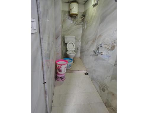a small bathroom with a toilet and a pink bucket at Hotel Guru International Andaman in Aberdeen