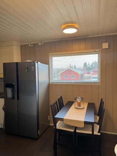 a kitchen with a refrigerator and a table with chairs at Sentral familievennlig enebolig in Åmot