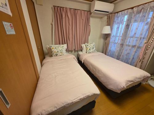 神戸市にあるTakaraboshi room 301 Sannomiya 10 minの窓のある小さな部屋にベッドが2つある
