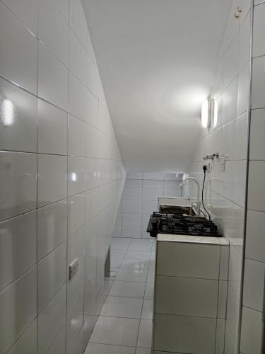 a white tiled kitchen with a stove top oven at Hidalgo Home Apartment's in Moshi