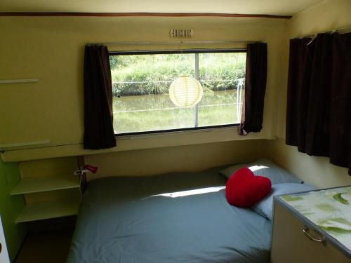 ein kleines Schlafzimmer mit einem Bett mit Fenster in der Unterkunft nuitée insolite aux berges d'un canal tranquille 