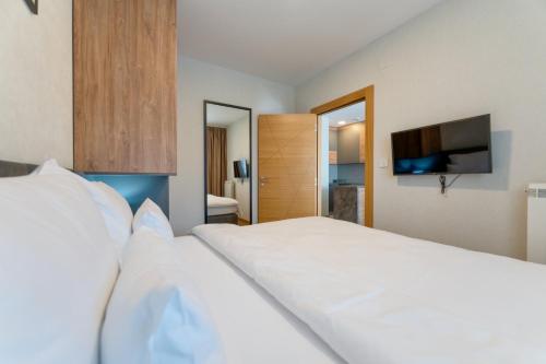a bedroom with a large white bed with a flat screen tv at Mountain Pearl Zlatibor in Zlatibor