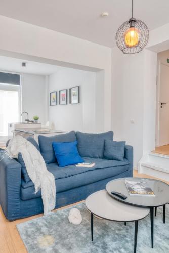 a living room with a blue couch and two tables at 4 Beautiful Apartments in the Center of Ieper in Ypres