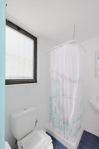 a white bathroom with a toilet and a window at Eco Beach And Magic Garden Hotel in Gennadi