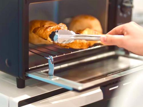 a person is taking food out of an oven at HOTEL minimumms女性専用カプセルホテルWomen only hotel in Naha