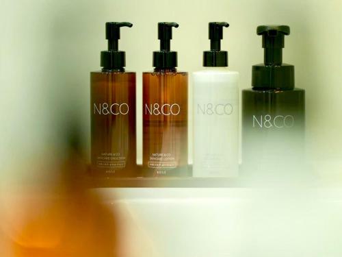 a group of three bottles of sunscreen on a shelf at HOTEL minimumms女性専用カプセルホテルWomen only hotel in Naha