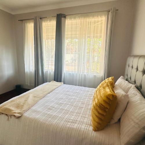 a bedroom with a white bed with a yellow pillow on it at MBT Lodge in Polokwane
