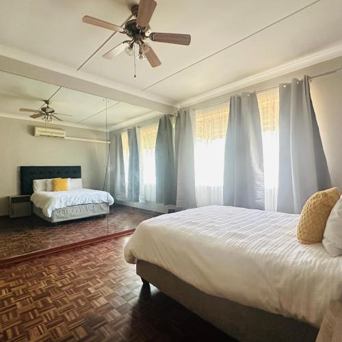 a bedroom with two beds and a ceiling fan at MBT Lodge in Polokwane