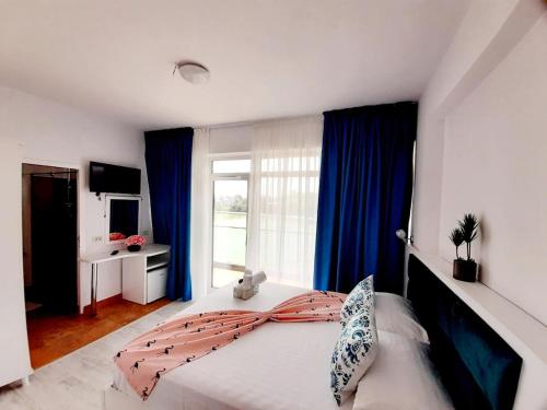 une chambre avec un grand lit avec des rideaux bleus dans l'établissement Tasos - Rooms with see View, à Eforie Nord
