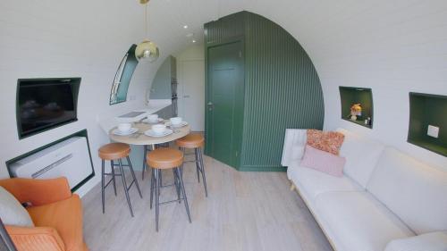 a living room with a couch and a table and chairs at Eira Pod - Luxury Glamping escape - private Hot tub in Pembroke