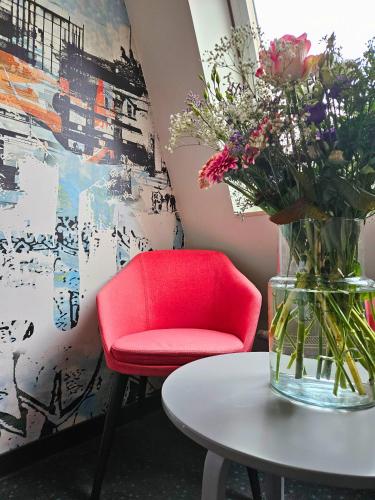 a red chair and a table with a vase of flowers at Good Morning Berlin City West in Berlin