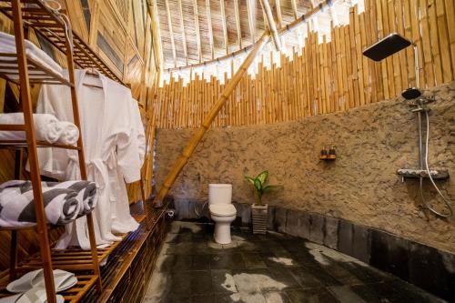 a bathroom with a toilet in a room with wooden walls at Velonia Iseh in Sidemen