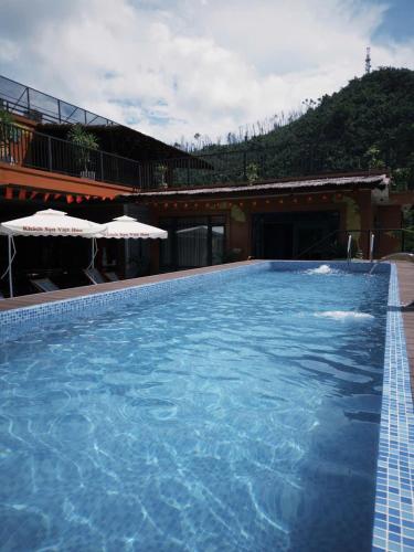 a large blue swimming pool with umbrellas next to a building at Cat Ba Viet Hoa Hotel & Residence - Pool & Bar in Cat Ba