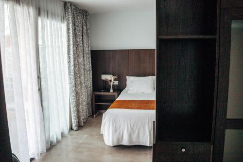 a bedroom with a bed with white sheets and curtains at Hotel Alba Seleqtta in Lloret de Mar